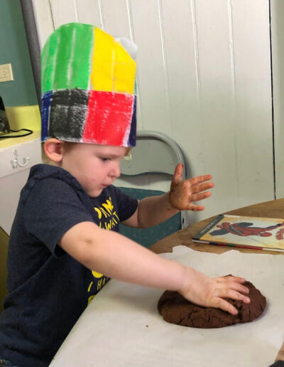 A young boy working his hands with clay