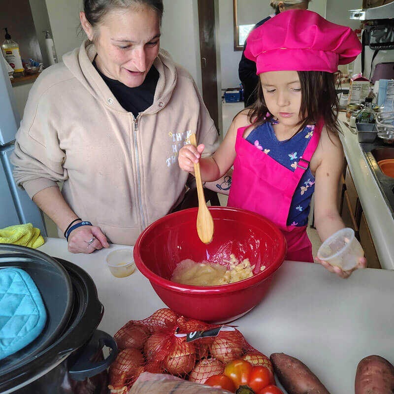 A young girl mixing ingredients while a female adult observes