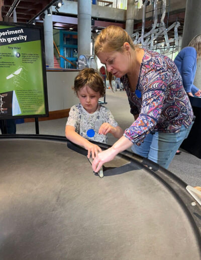 An adult helping a young child at a science exhibit