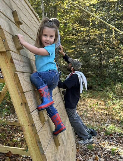 A young girl climbing a climbing wall with her dad