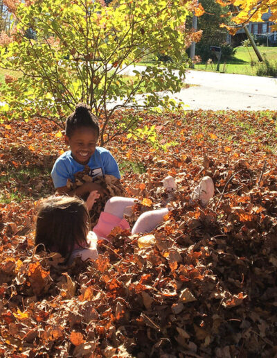 Two young girls playing in a pile of leaves