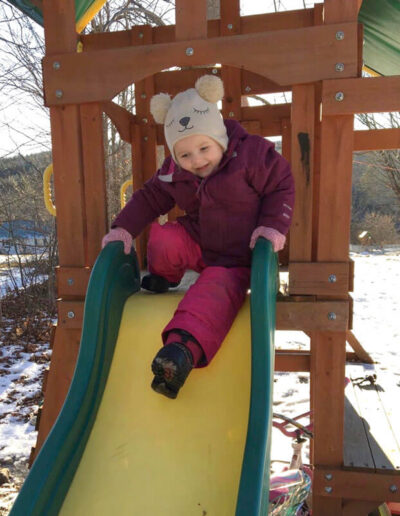 Young child in winter clothes at the top of a slide