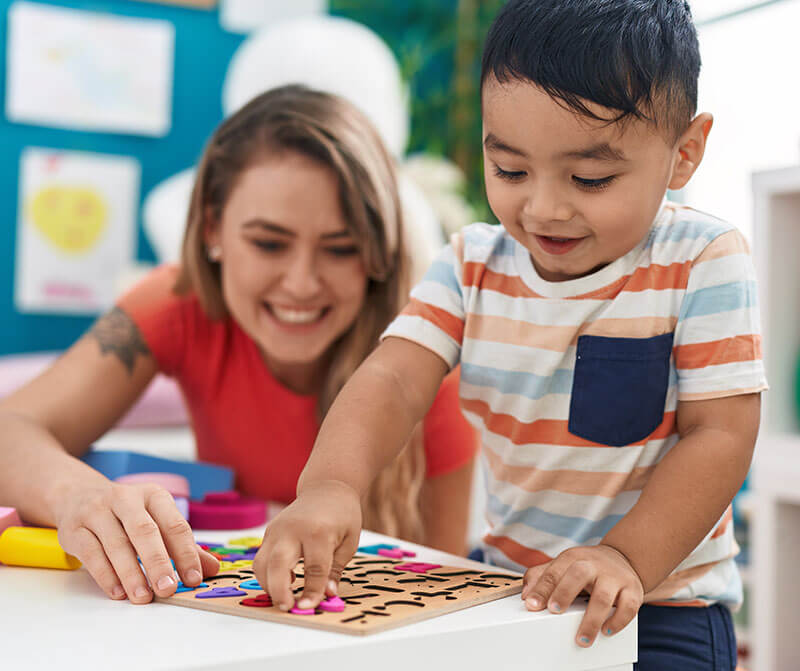 Teaching working on a puzzle with a young boy